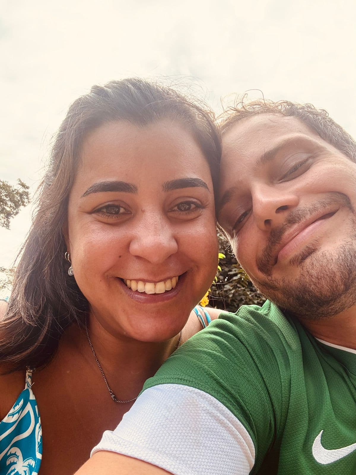Camila e Ricardo juntos, sorrindo para a foto ao ar livre